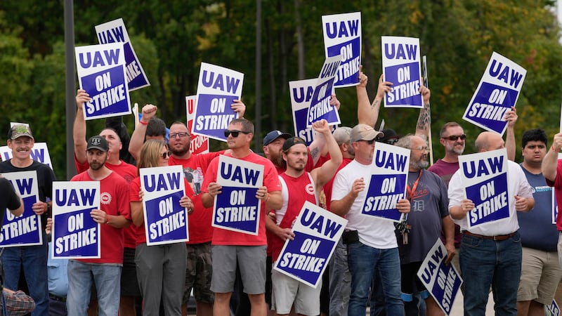 FILE - United Auto Workers members hold picket signs near a General Motors assembly plant in...