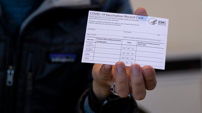 FILE - A nurse practitioner holds a COVID-19 vaccine card at a New York Health and Hospitals...